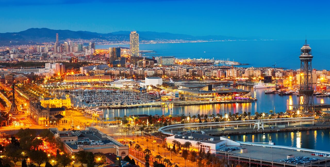 Barcelona waterfront skyline at dusk with marina, city lights, and Mediterranean coast