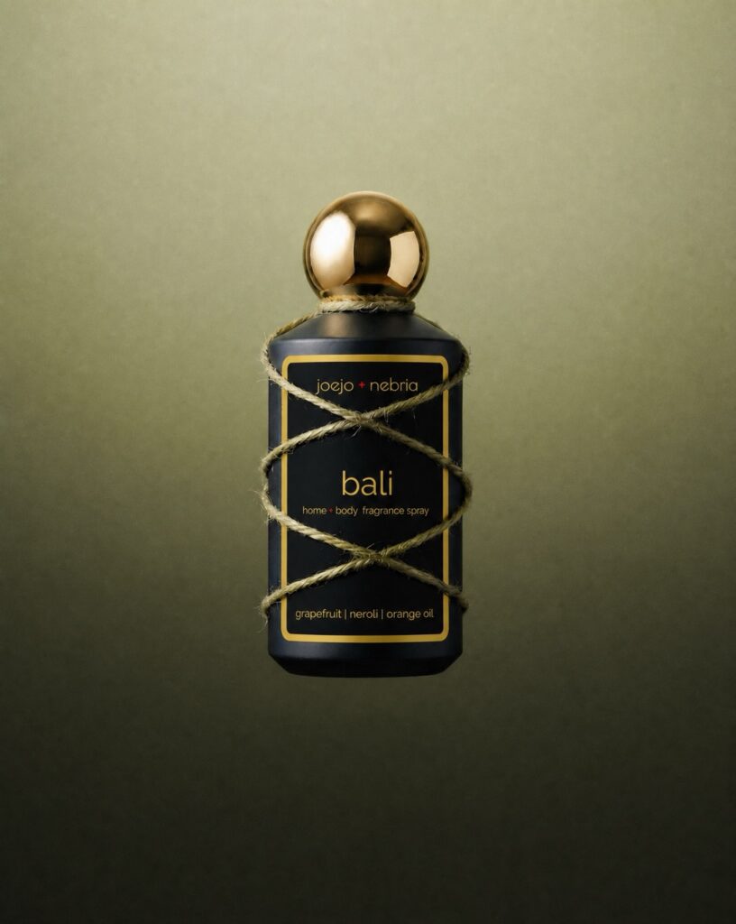 JoeJo + Nebria Bali Home + Body Fragrance Spray featuring grapefruit, neroli, and orange oil fragrance notes, wrapped in natural rope detailing against a soft green gradient background.